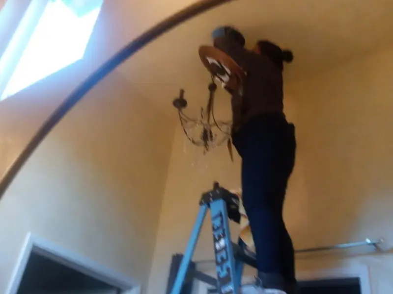 Electrician installing a chandelier in a Chesapeake Ranch Estates residence